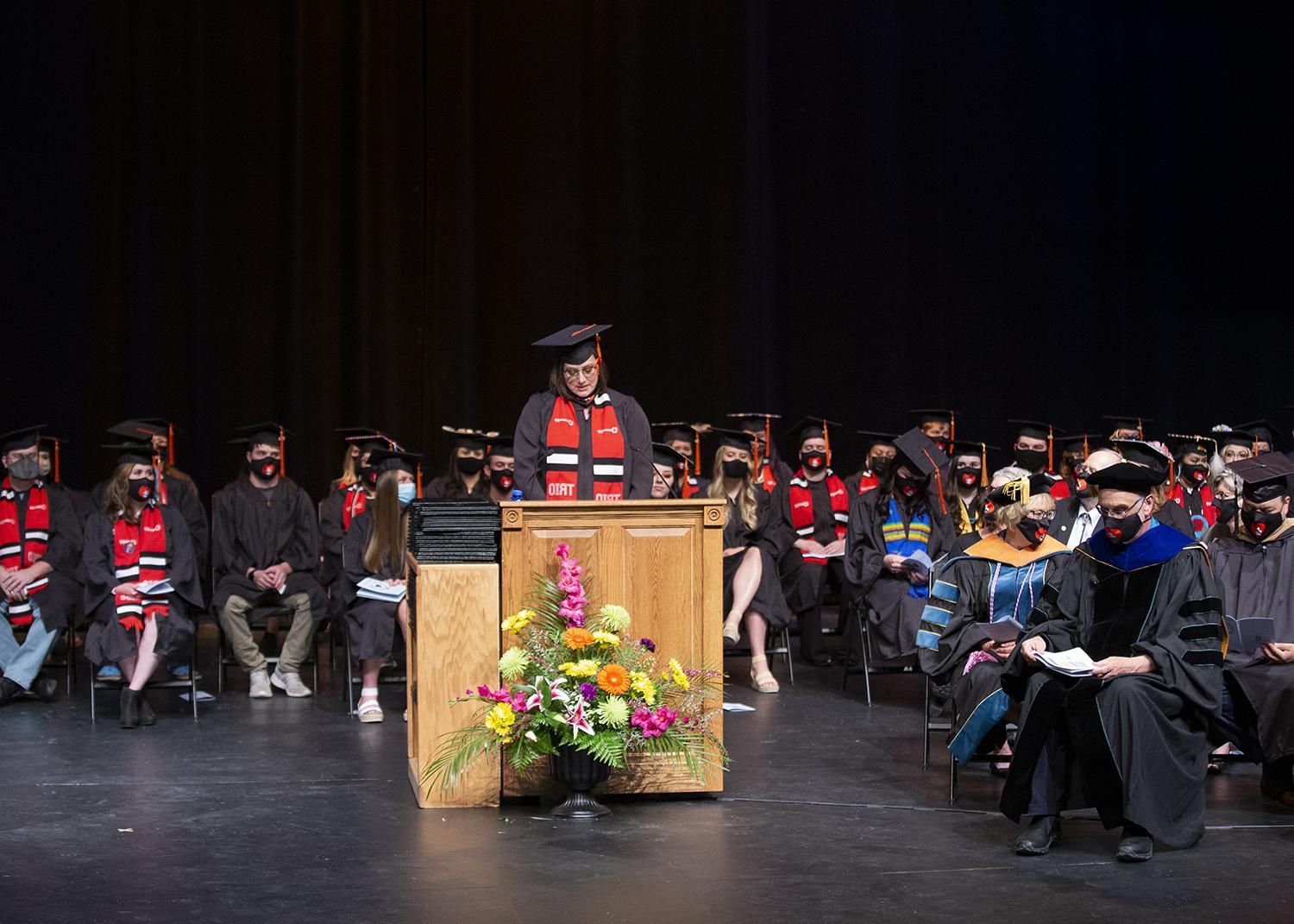 毕业生演讲人站在讲台上，与台上的毕业生站在一起